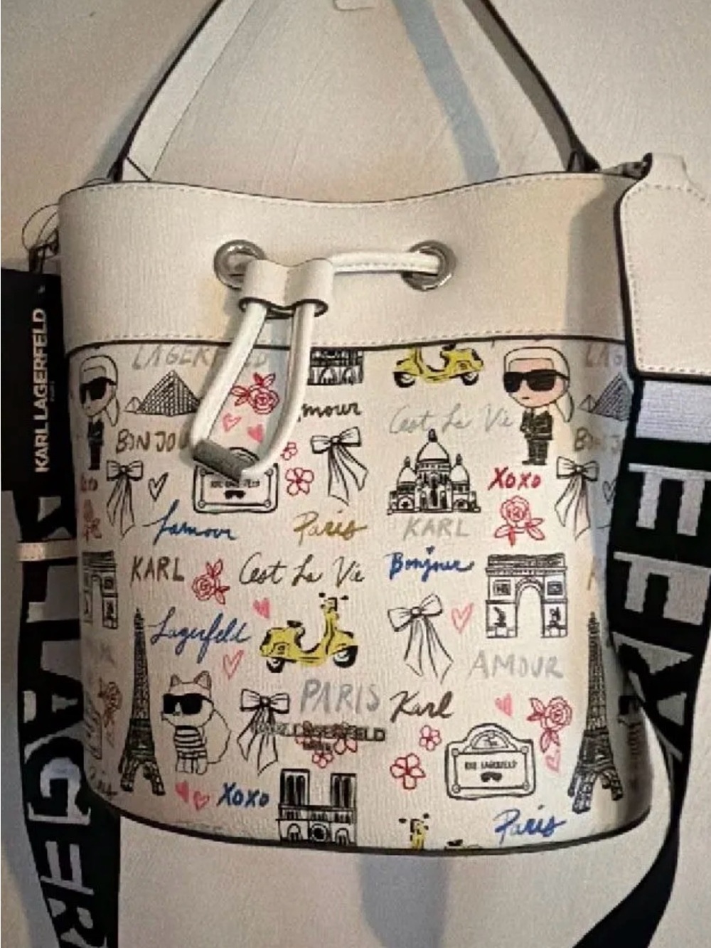 Karl Lagerfeld White Drawstring Paris Sketch Bucket Bag with Black Guitar Strap.